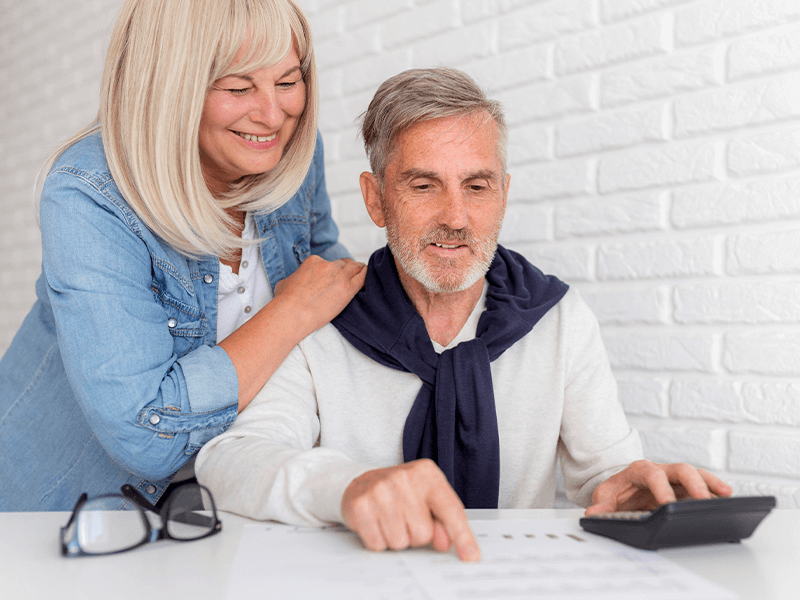 Two people at a table with documents and a calculator, one comforting the other.