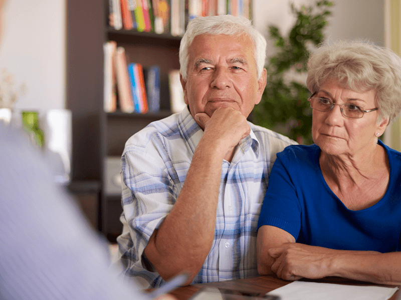 Two senior individuals sitting together with documents on the table.
