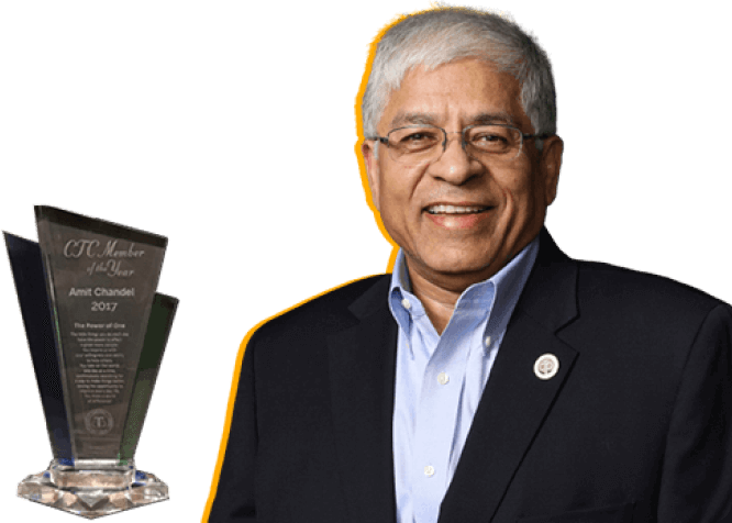 Amit Chandel in suit with award trophy, on a black background.