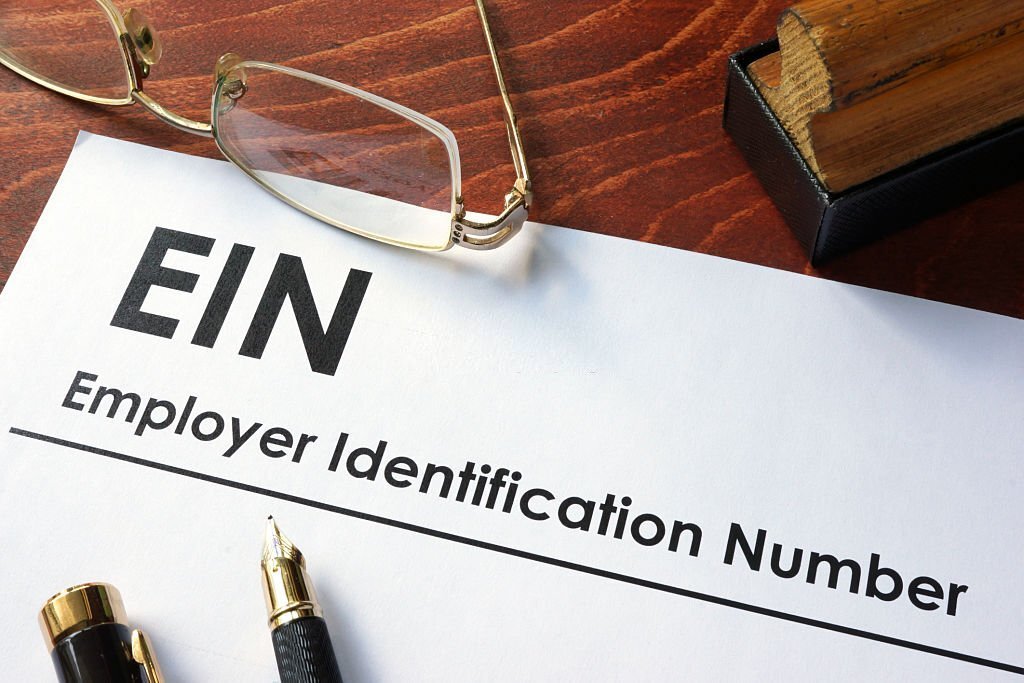 Paper with "EIN Employer Identification Number" beside glasses and a pen.