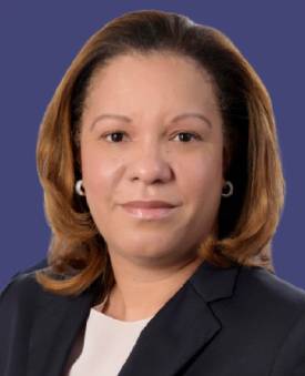 Lynn with shoulder-length hair wearing a navy blue blazer and white top against a blue background.