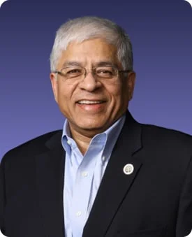 Amit Chandel in a black blazer and blue shirt against a blue background.